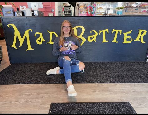 Ashlynn Harding is featured in the middle of the Mad Batter sign holding her two main reviewed cupcakes, the chocolate and red velvet. 