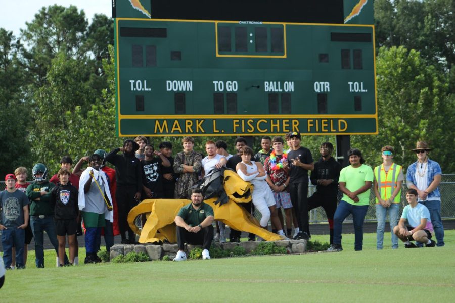Varsity players wearing student section themes sit on the field in front of the new scoreboard.
Photo by Ellen Rosson