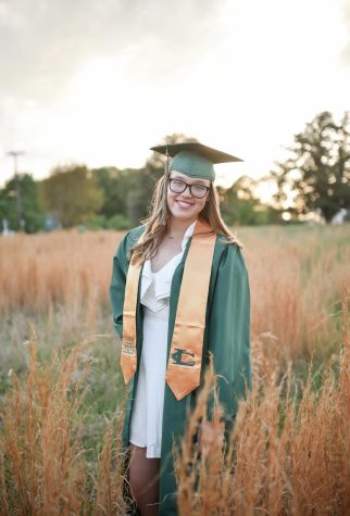 Senior and Editor in Chief, Ashlynn Harding poses in a field with her cap and gown for her graduation photos that were taken by April Summers. 