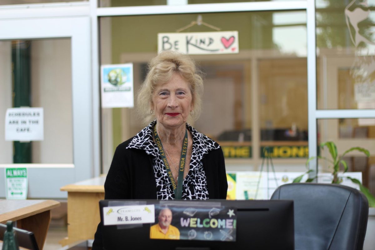 Ms. Tester monitors the front desk and greets everyone, wishing them a Happy Wednesday.