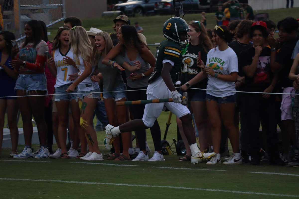 Senior Isaiah Haywood high fives the student section after exiting the tunnel.