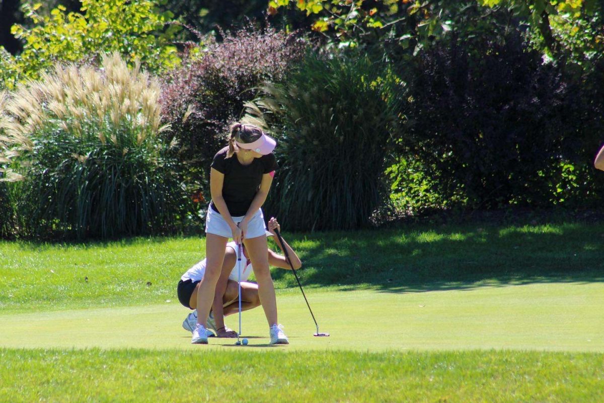 Sophomore Ava Garrison setting up her putt, and preparing to make it into the hole. 