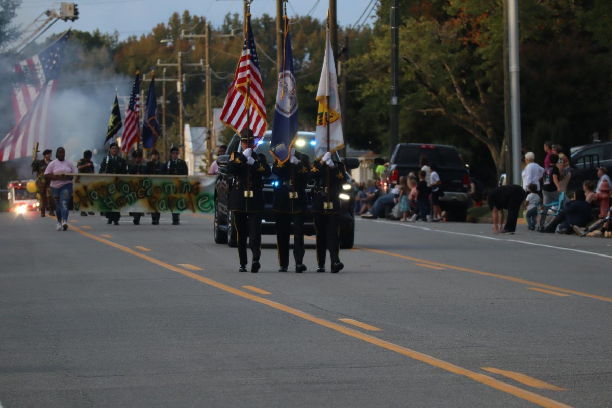Officers begin the 2023 homecoming parade by walking with the national, state, and local flags