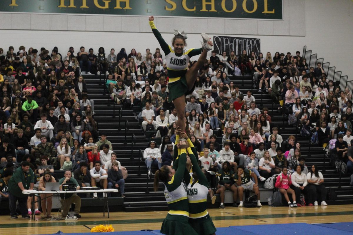 Senior Amaya Johnson being lifted up in the air while doing a heel stretch during competitions cheers pep-rally routine 