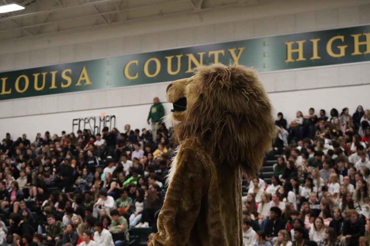Louis A. Lion standing on the court in front of the students, ready for the pep rally