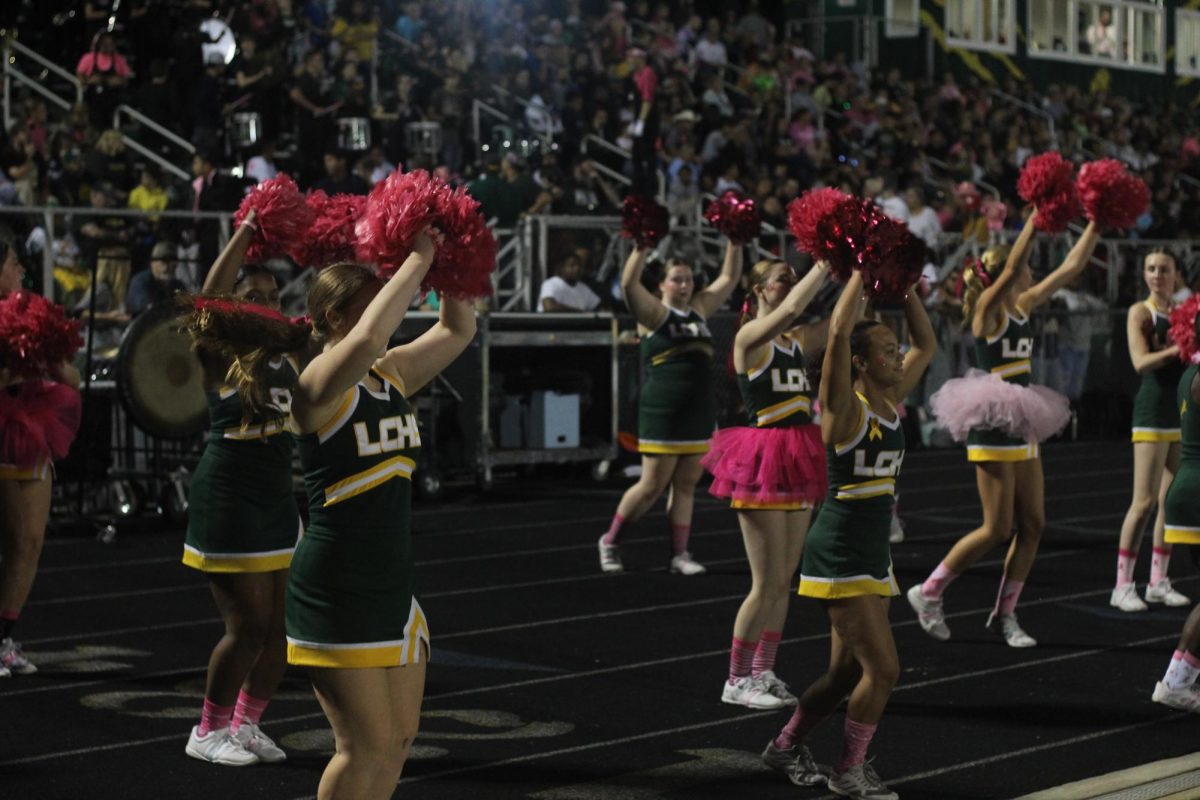 The sideline cheer team cheering on the football team as they try to get a defensive stop. 
