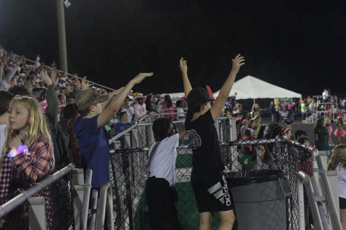 Young fans trying to catch a t-shirt being thrown after the football team scores a touchdown.