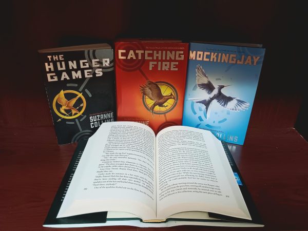 Original Hunger Games series by Suzanne Collins sits behind open A Ballad of Songbirds and Snakes book 