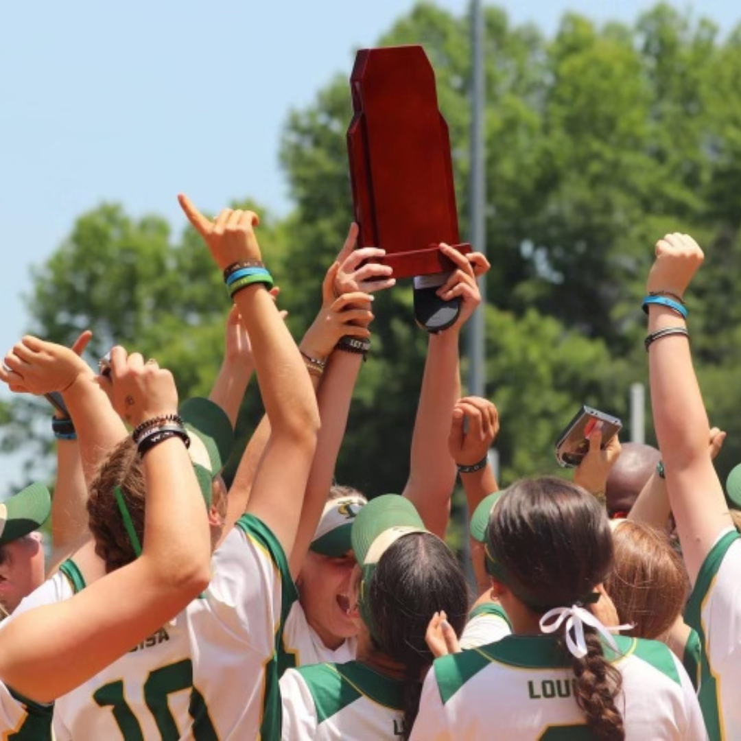 The varsity softball team holding up their state championship trophy as they celebrate their win.