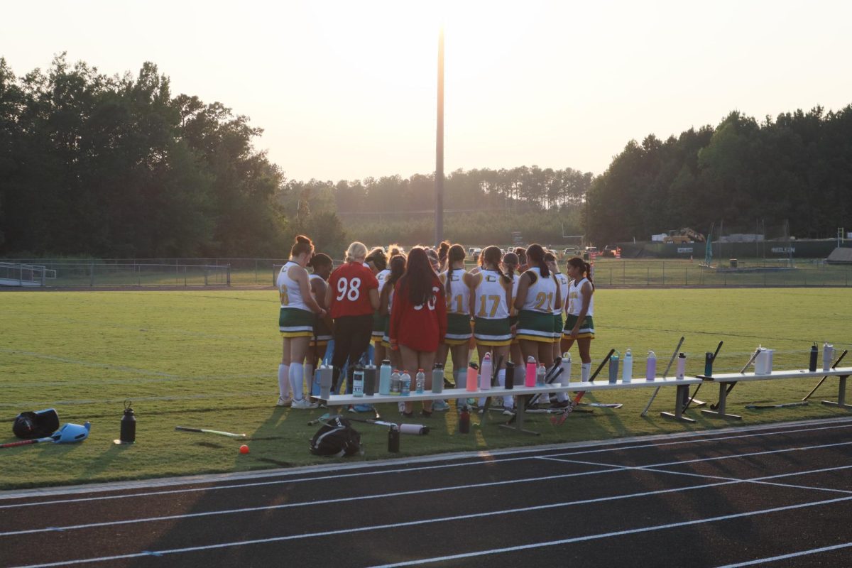 The Varsity girls field hockey team huddles up before their game begins.
