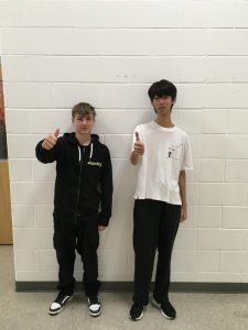 Exchange students Robin Hache and Ji-Won Hong give a thumbs up in the band hallway. 
