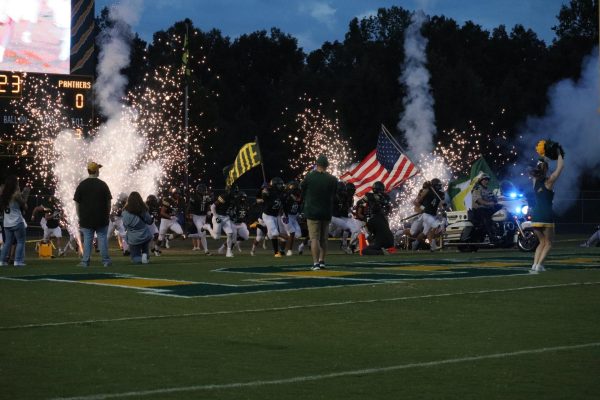 The varsity football team makes their thrilling entrance as the game is about to start.