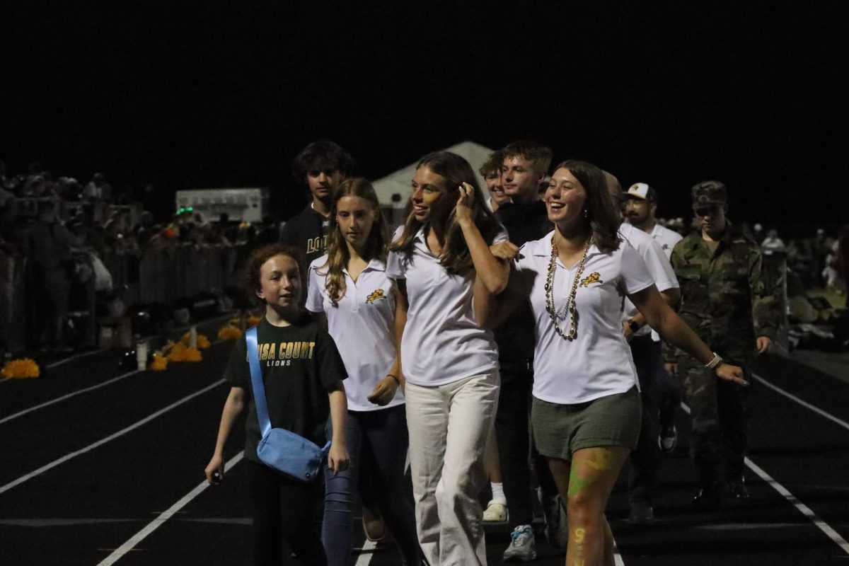 The golf team walks down the straight away of the track for fall sport recognition night.