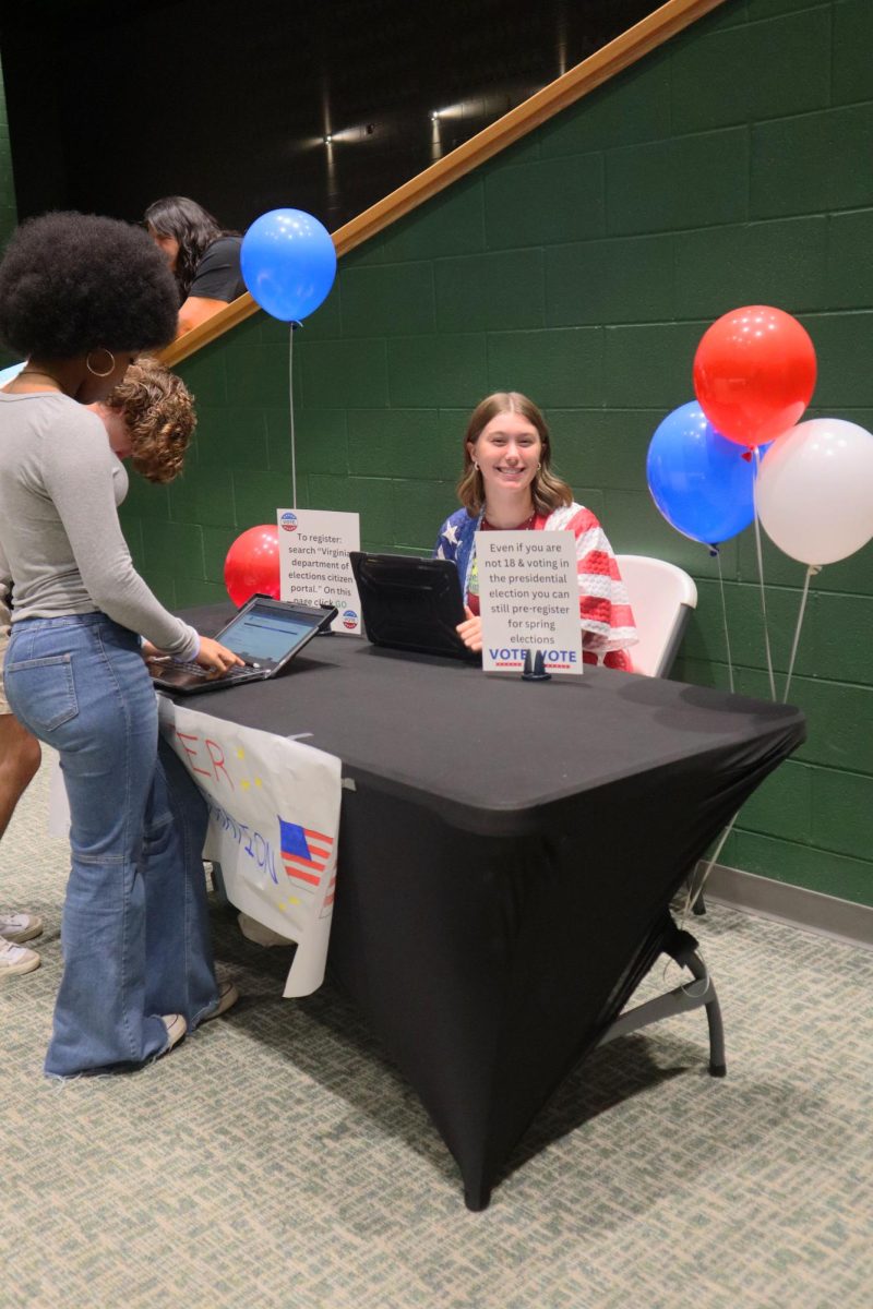 Gabi McGehee smiles as she helps seniors register to vote in the upcoming election