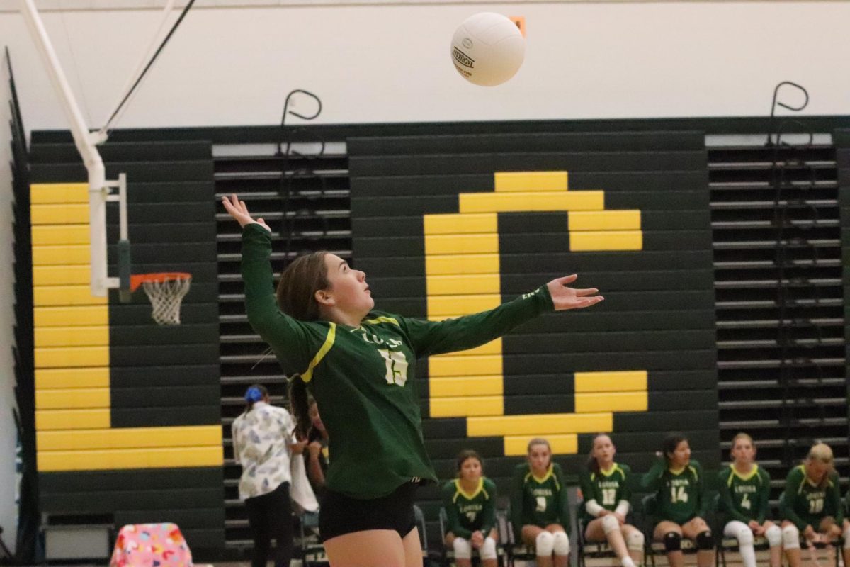 Eighth grader Graceyn Monahan is serving the ball over the net.