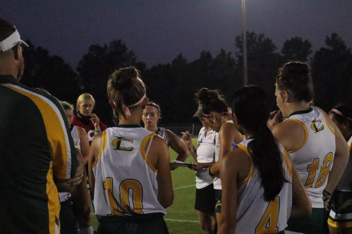 During the break, The field hockey athletes come together to listen to their coach strategize. 