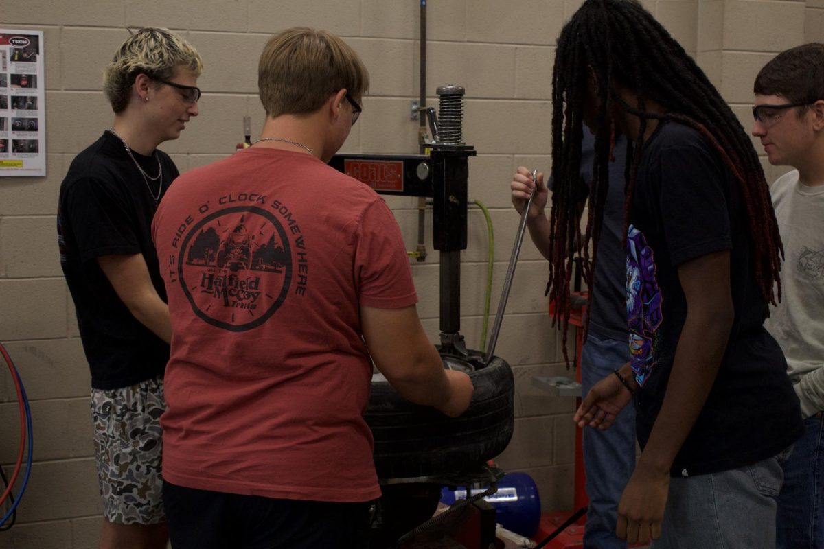 Auto 1 students remove a tire off the rim with the tire machine. 