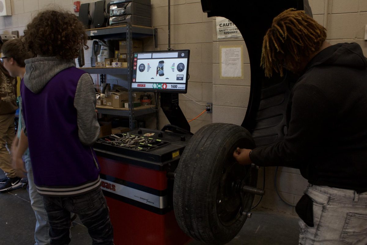 Auto 1 students add weights to balance a wheel.