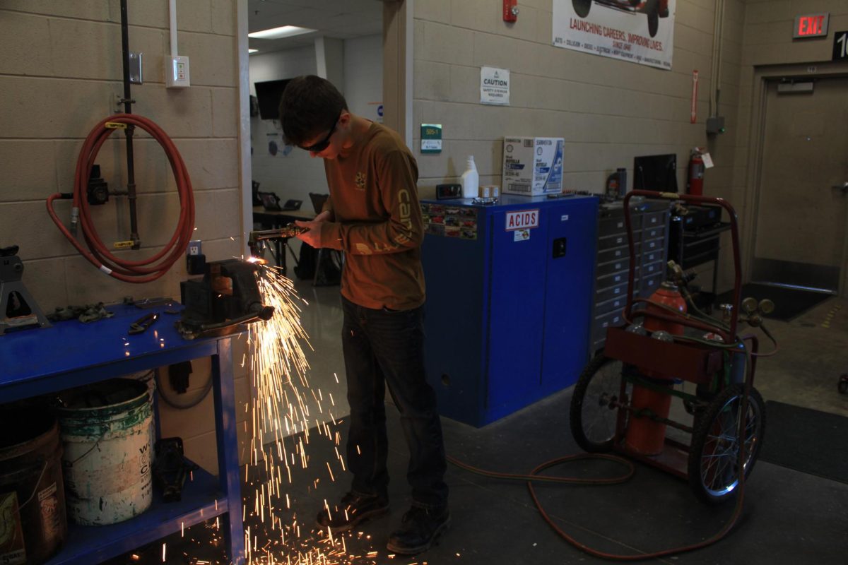 Auto 1 student use a torch to burn a metal plate to practice with the tools.
