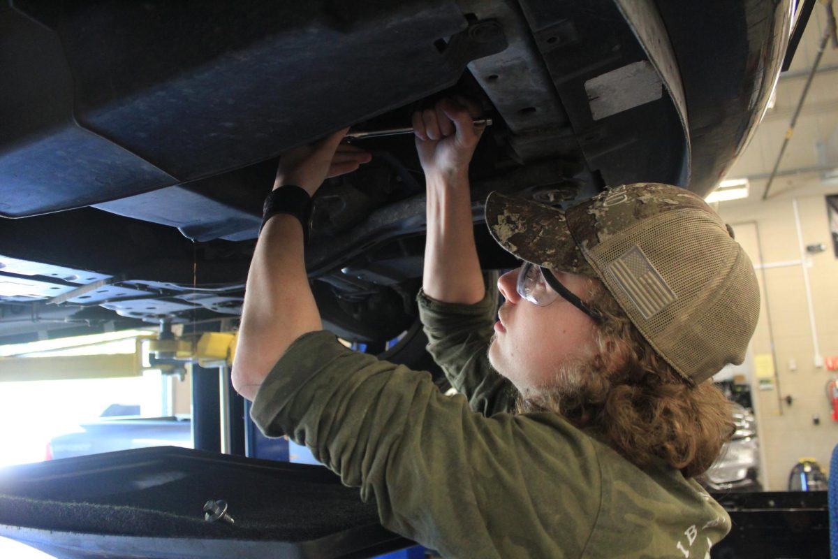 Auto 2 student removes the oil filter to perform a basic oil change.