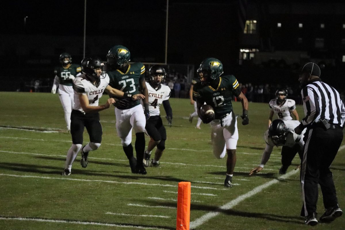 Junior Dyzier Carter carries the ball down the sideline, while running back Savion Hiter blocks a Charlottesville player.