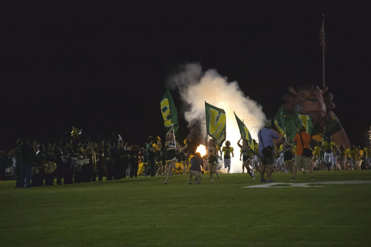 The band watches as the varsity football team enters the field for Friday Night Lights.