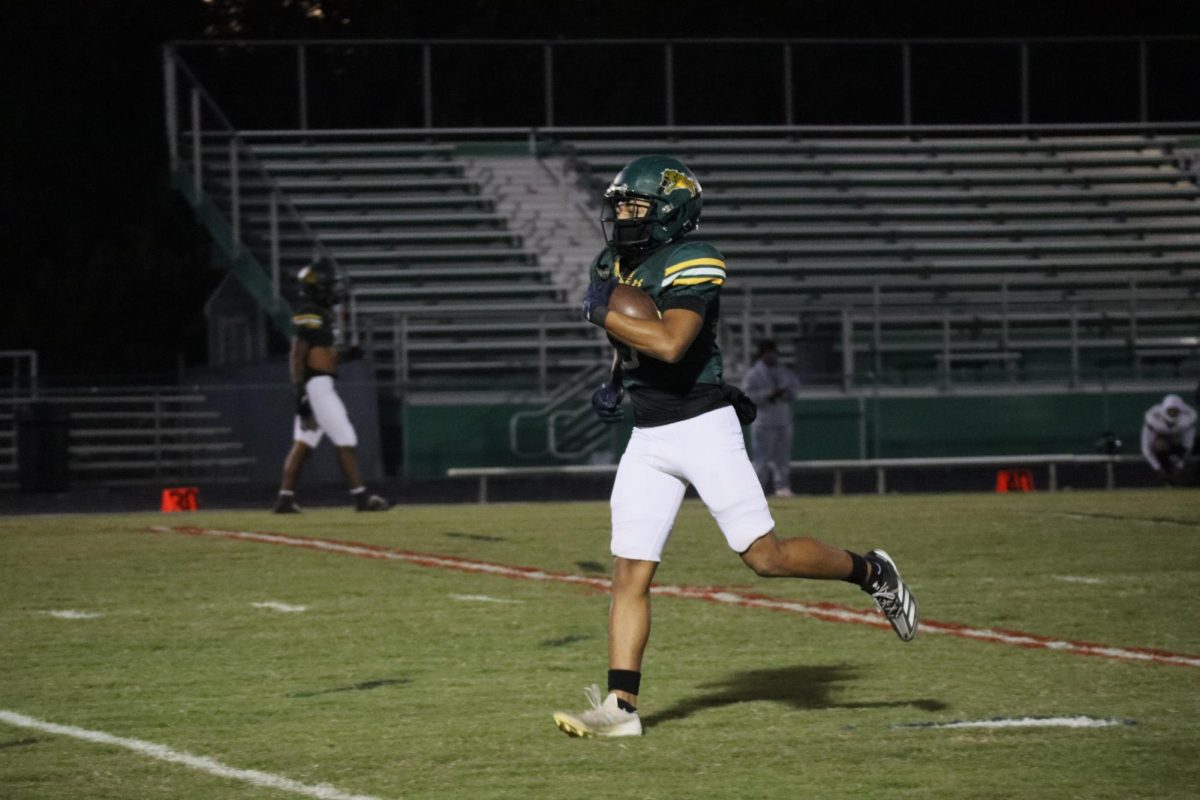 Sophomore Dustin Nelson receives the ball and runs towards the end zone during warm ups.