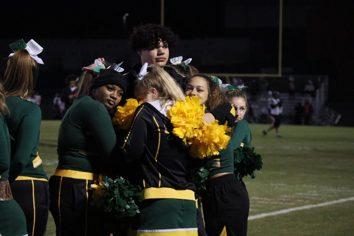 The cheer team huddles together in order to keep warm before the game. 