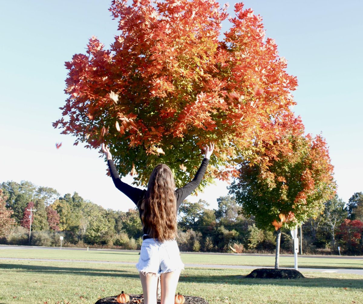 Outside in the fall weather, junior Mackenzie Randlett is throwing the fallen leaves, admiring the beauty of nature