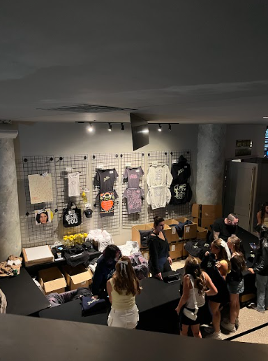 The merch stand displays items like sweatshirts, posters, and tote bags.