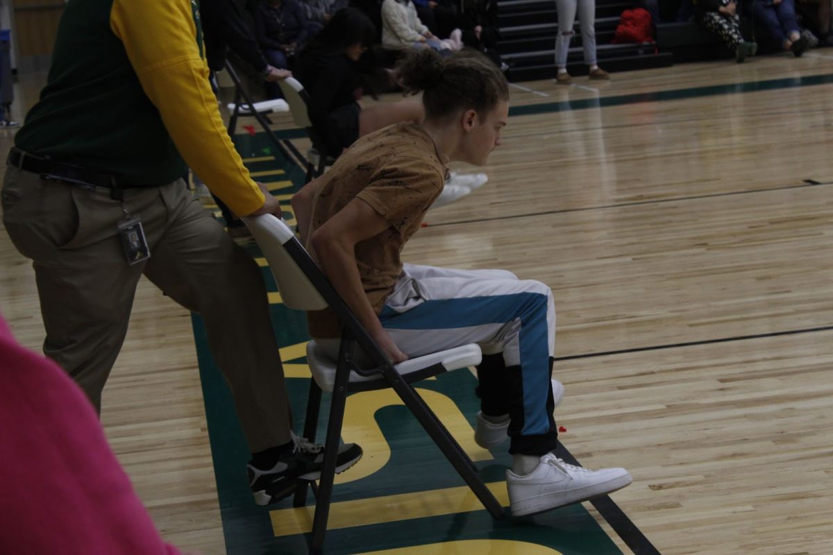 Sophomore Tyson Whiteside quickly sits down on a balloon during the balloon relay pep rally game.
