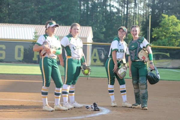 Hopkins (Far Right) and Kidd (Middle Right) stand on the mound with teammates Kalli Monahan (Far left) and Lily Ruckle (Middle left) before their softball game. (Courtesy of Alyssa Hopkins)
