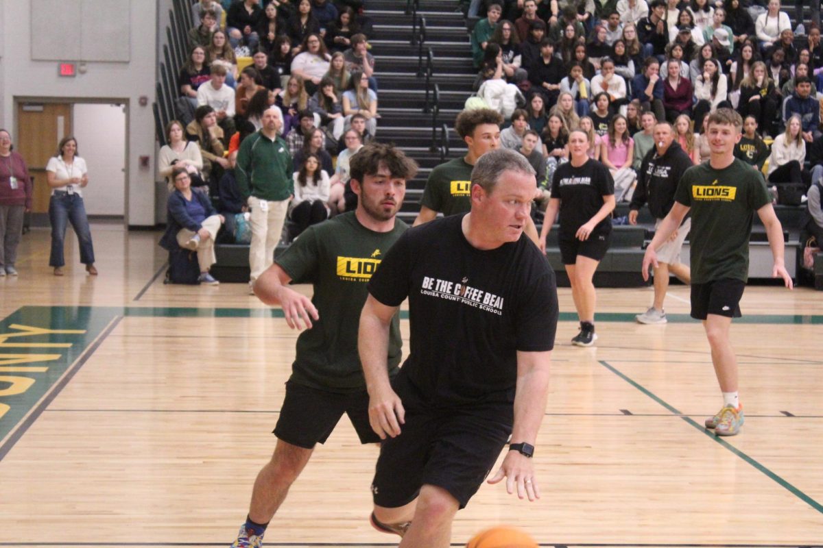 Athletics Director, Mr. Barrett, takes the ball up the court during the Senior vs. Teacher basketball game. 