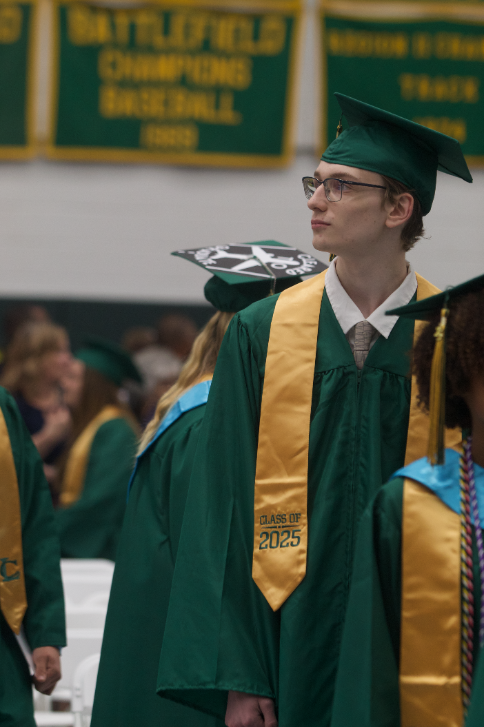 Graduate Ryan Dumire walking into the gymnasium looking for his family as he finds his seats.