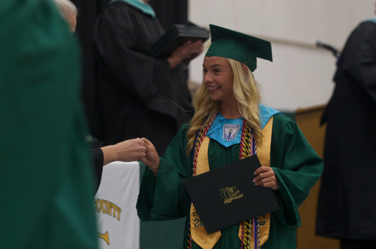 Senior Madison Hiter is given her first dollar coin by Dr. Thiemann as a newly graduate.