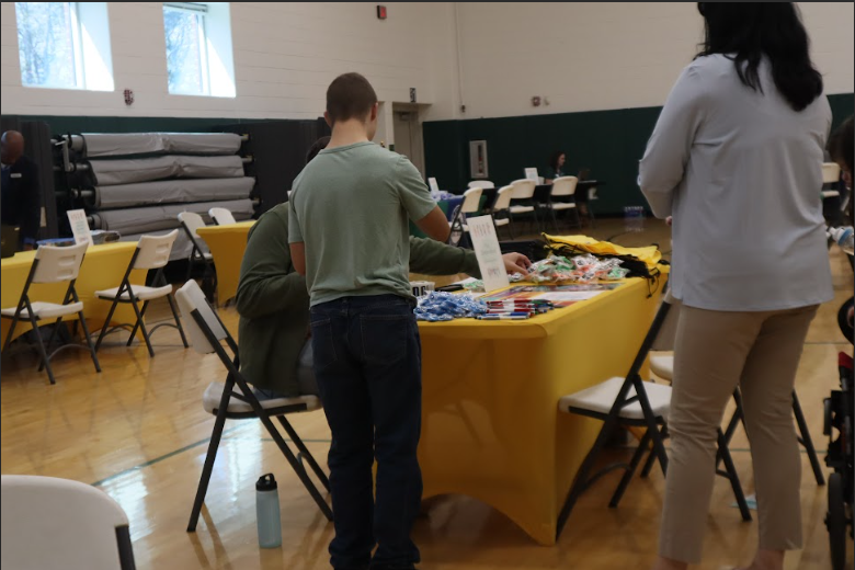 Malachi Rodgers stands with his mom, Clare Rodgers, as they collect small gifts from one of the tables.