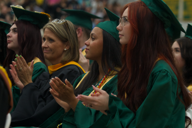 Seniors sit at graduation, clapping for each other as they prepare to take their next steps beyond high school.