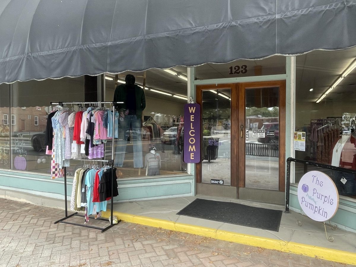 Clothes hang outside of the store along with a welcome sign, welcoming customers in.