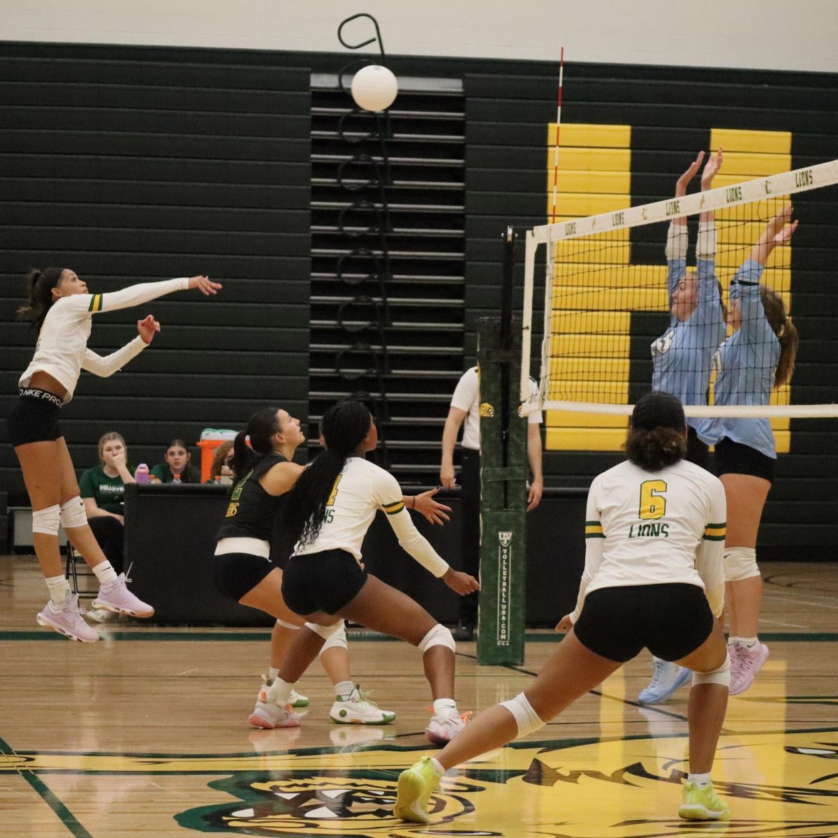 Martinez hits the ball over the net, while Moreano and Williams prepare for the block. 
