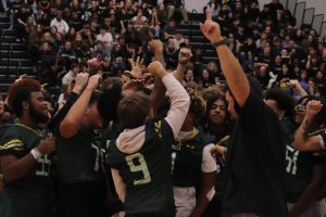 After Coach Patrick's speech, the football team gathers in the middle of the gym to start their chant.
