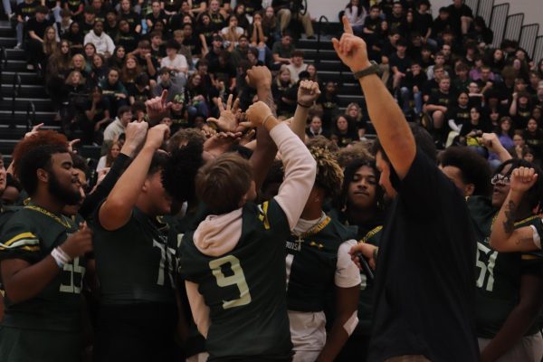 After Coach Patrick's speech, the football team gathers in the middle of the gym to start their chant.
