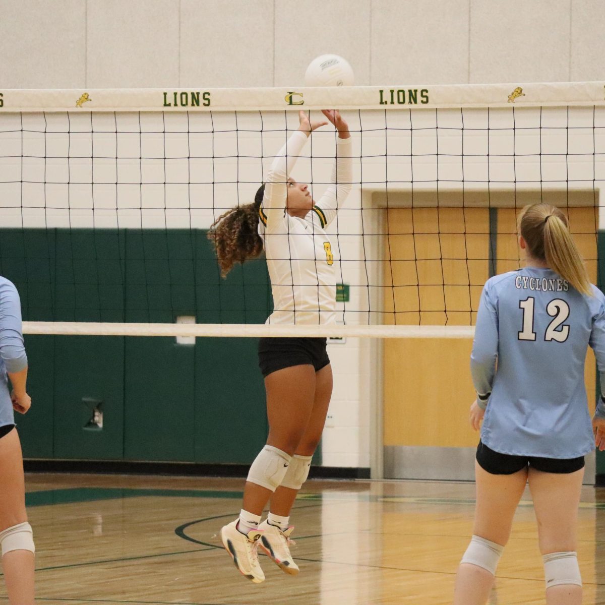 Green sets the ball for her teammate while the opposing team gets ready for the spike. 