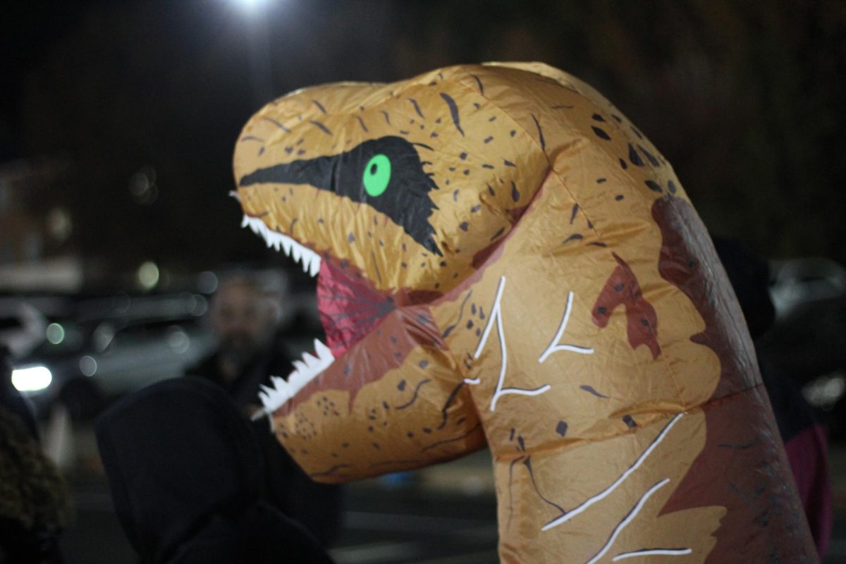 A trunk or treater dresses up in a inflatable dinosaur costume.