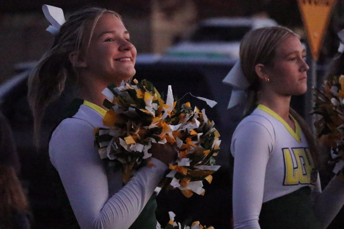 Cheerleaders Austyn Frame and Alydia Spencer cheer on the other floats in the homecoming parade.