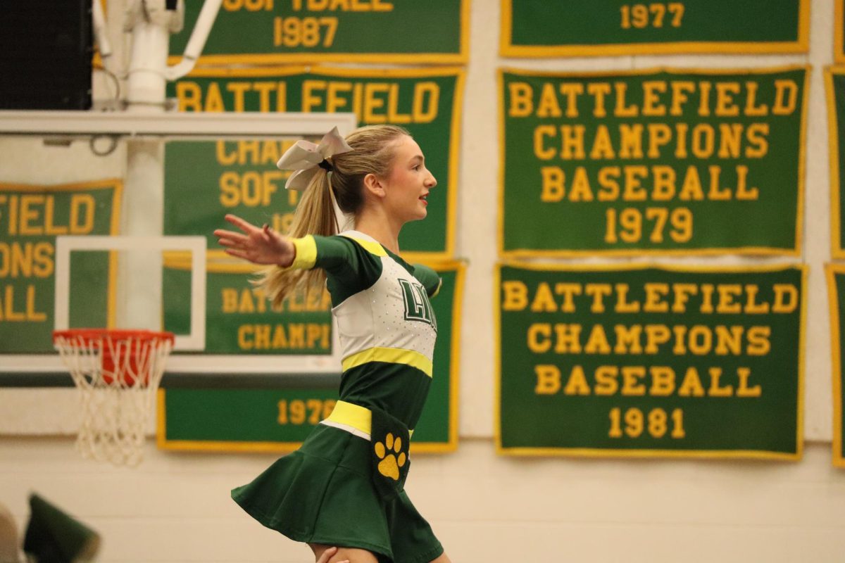 Flyer Millie Jay is being held by her base, while she looks out into the crowd of students.