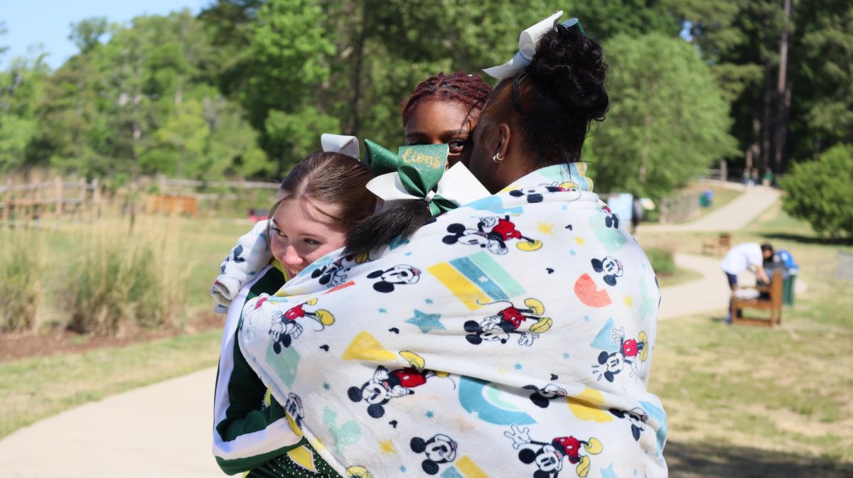 The cheerleaders wait for the arrival of Ms. Fletcher and embrace each other to keep warm. 